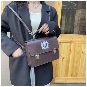 Macro shot of British retro brown leather messenger bag with embroidered school crest
