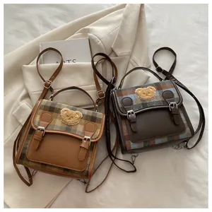 Detail view of retro plaid backpacks with plush bear badge and leather trim in two colors