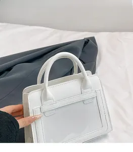 Dettaglio borsa a mano bianca minimalista con scomparto in PVC e doppi manici tondi