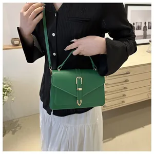 Close-up of green leather crossbody bag with gold metal buckle on a model's arm