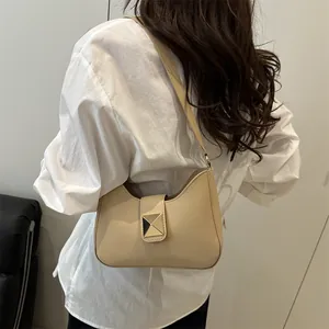 Elegant beige leather half-moon shoulder bag with square metal stud on model back view
