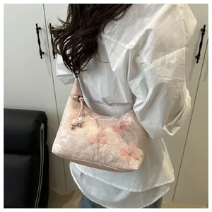 Detail of pink lace shoulder bag featuring 3D butterfly accents and pearl pendants