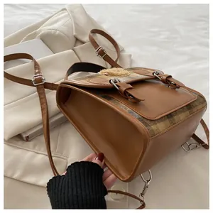 Detail view of vintage plaid backpack with faux leather trim and dual buckle design