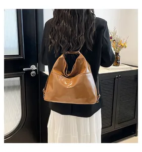 Polished brown tote bag detail with adjustable strap and silver metal hardware