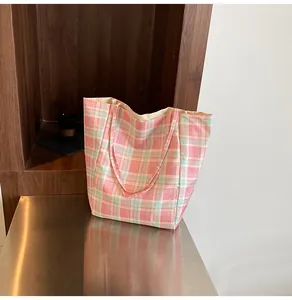 Detail of pink and light green checkered canvas tote bag on a metallic surface