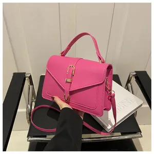 Detailed close-up of vibrant pink leather handbag with gold metal clasp and top handle