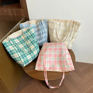 Close-up of stylish plaid tote bags in pink, green, blue, and yellow fabric on a table