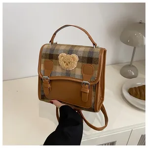 Detail of vintage brown plaid backpack with a cute 3D plush bear patch on the front flap