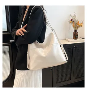Close-up of a white glossy hobo bag with outer pocket on a shoulder-carried model