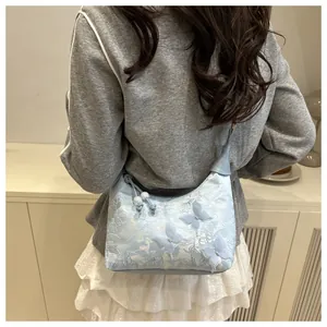 Detail of light blue hobo bag featuring delicate lace embroidery and 3D butterfly appliques