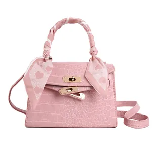 Pink crocodile pattern handbag with heart scarf detail and gold clasp closure