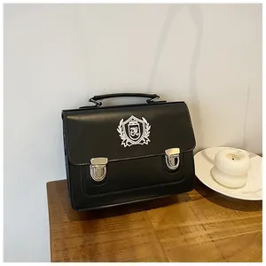 Detail of black JK uniform bag featuring embroidered silver shield badge and metal buckles