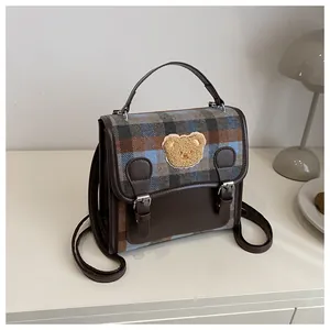 Close-up of retro plaid fabric texture and cute bear patch on the leather flap bag