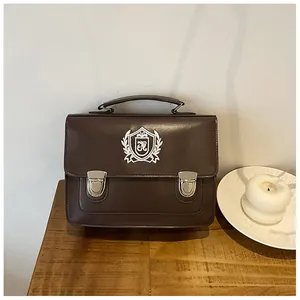 Detail of a brown vintage JK uniform bag with white shield embroidery and metal buckles