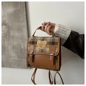 Detail of vintage plaid backpack with a cute teddy bear patch and brown leather straps