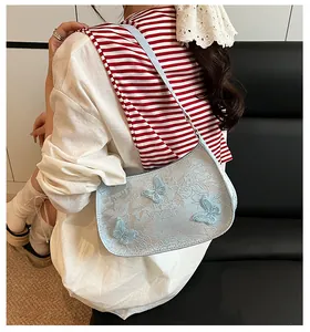 Détail du sac à bandoulière bleu clair avec broderies et appliques papillon en 3D