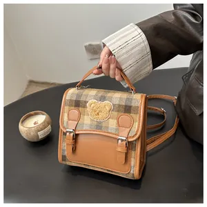 Close-up of retro plaid mini bag featuring a cute bear patch and premium leather straps