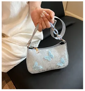 Detailed close-up of light blue lace handbag with 3D butterfly embroidery and chain strap