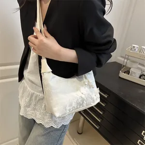 Elegant white embroidered pillow bag with floral 3D details shown on model's shoulder