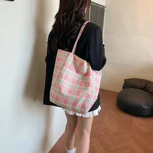 Pink and green plaid canvas tote bag with a large capacity shown on a model's shoulder