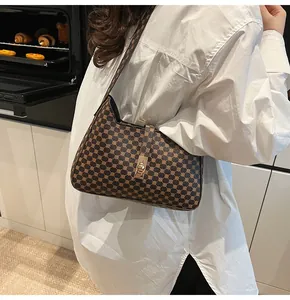 Détail du sac porté épaule marron vintage avec motif monogramme et fermoir doré chic