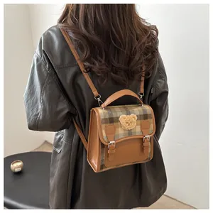 Rear view of a stylish small plaid backpack with leather trim and bear patch detail