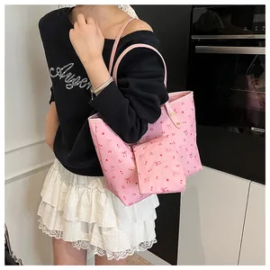 Détail d'un sac cabas rose avec imprimé cerise et pochette porté par un mannequin