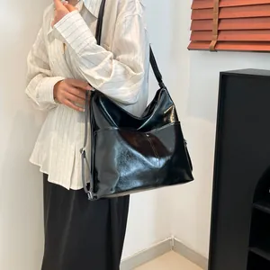 Large black glossy tote bag with soft leather texture and stylish shoulder strap detail