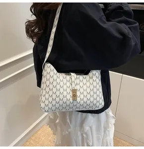 Détail d'un sac sous les bras blanc avec imprimé M et boucle métallique dorée chic