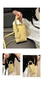 Details einer hellgelben kleinen quadratischen Handtasche mit Lederanhänger in Hundeform
