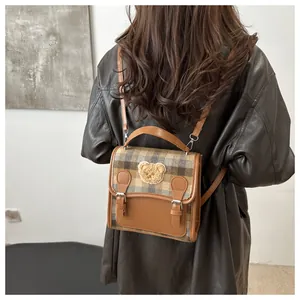 Detail of vintage plaid mini backpack featuring a plush bear patch and leather straps