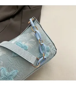 Detailed macro view of light blue bag featuring butterfly embroidery and resin chain strap