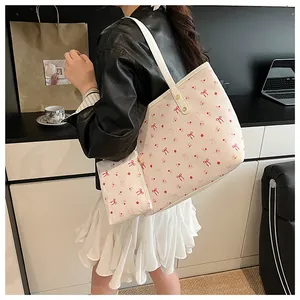 Gros plan d'un sac cabas écru avec imprimés cerises et sa petite pochette assortie