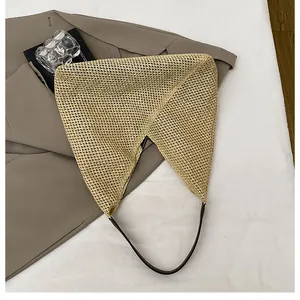 Flat lay of a woven geometric shoulder bag with brown leather straps and paper straw texture