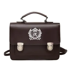 Dark brown JK school style leather satchel with top handle and embroidery shield logo