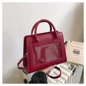 Dettaglio borsa in pelle PU bordeaux con tasca in PVC trasparente su fondo strutturato