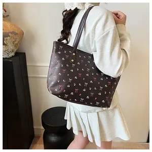 Grand sac cabas marron avec motifs de nœuds roses porté par un mannequin en salle