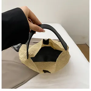 Close-up of woven straw bucket bag showing black leather handle and inner lining texture