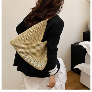 Macro detail of beige woven straw shoulder bag with geometric folding and texture