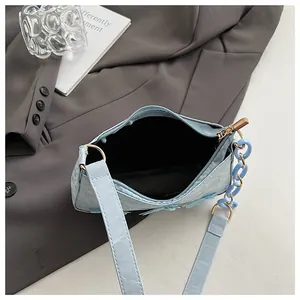 Detailed close-up of light blue handbag showing zipper closure and floral embossing