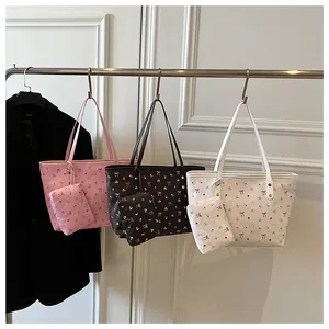 Détail du sac cabas floral avec imprimé cerises et pochette assortie sur un support