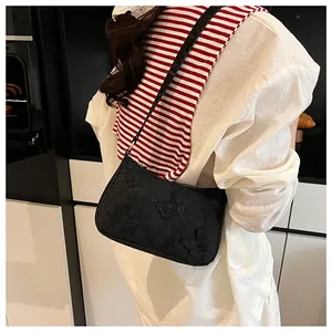 Detail of elegant 3D butterfly embroidery on black textured fabric shoulder bag