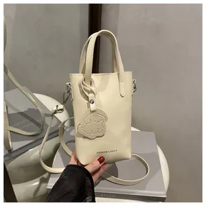 Detail of cream mini square bag with dual handles and cute puppy leather charm accessory
