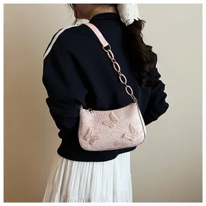 Detail of pink shoulder bag with 3D butterfly embroidery and chain strap on a model