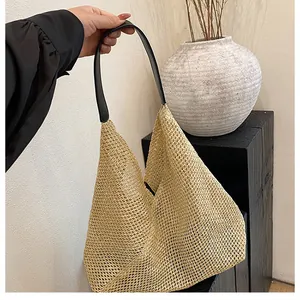 Detail of hand-woven beige straw tote with premium black leather handle and mesh texture