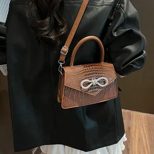 Brown crocodile embossed handbag with rhinestone bow buckle and adjustable strap