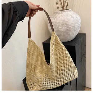 Close-up of woven straw handbag with brown leather strap against a minimalist background