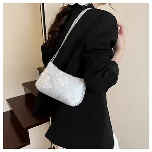 Detailed silver crescent shoulder bag featuring intricate butterfly embroidery on fabric