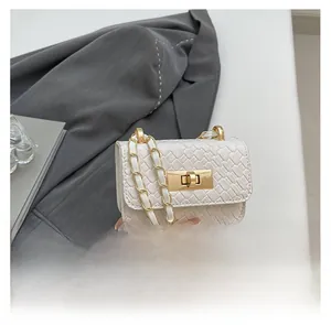 Close-up of white crossbody bag with crocodile texture, gold rotary lock, and chain strap