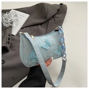 Close-up of light blue lace bag featuring 3D butterfly embroidery and acrylic chain detail